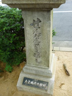 Açık havada işlenmiş Japon karakterlerin yer aldığı eskimiş taş bir anıt.