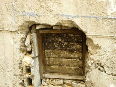 Yıpranmış beton duvar ve açıkta duran ahşap pencere çerçevesi