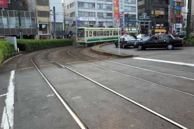Şehir yolunda hareket eden yeşil tramvay 