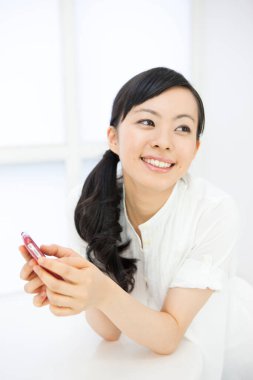 İç mekânında akıllı telefonu olan güzel Asyalı bir kadının portresi.