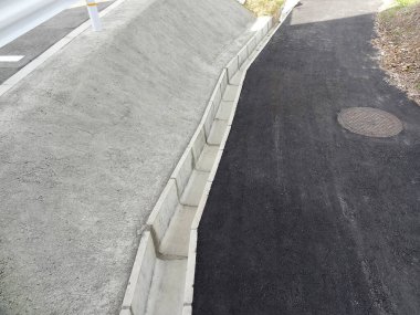 Beton drenaj kanalının yanında yeni asfalt yol açıldı.