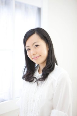 Zarif Japon kadın, temiz, parlak beyaz bir ortamda güven içinde poz veriyor..