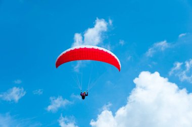 Mavi gökyüzü arka planında kırmızı paraşütü olan bir adam, yaz tatili