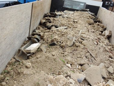 Kırık beton molozları büyük ahşap çöp konteynırının içine saçılmış.