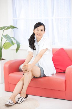 Kanepede oturan Asyalı kadın. 