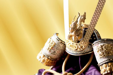 Sarı arka planda duran süslü samuray miğferi.