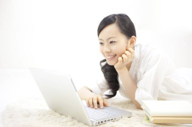 Göz kamaştırıcı bir Japon kadının portresi. Parlak beyaz bir odada dizüstü bilgisayarla çalışıyor..