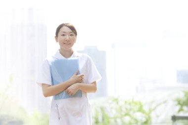 Dışarıda duran kitaplarla genç bir hemşire.