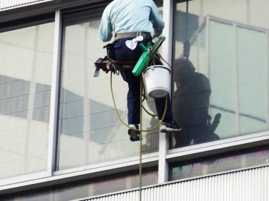 adam pencereyi fırçayla temizliyor.