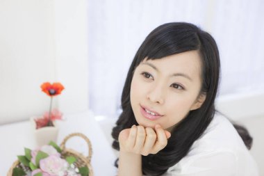 Zarif Asyalı kadın ışıl ışıl beyaz bir odada cazibe ve duruş ile poz verdi..