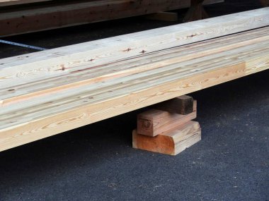 Küçük destek bloklarının üzerinde duran istiflenmiş ahşap tahtalar.