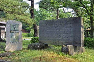 Yeşil çimlerin ve ağaçların arasında duran büyük taş anıtlar.