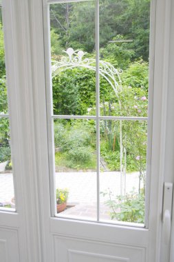 Pencerenin arka planında çiçekler olan beyaz pencere