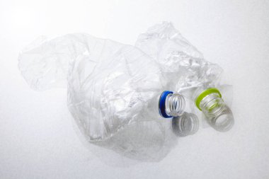 Şeffaf plastik poşetin yanında buruşmuş plastik şişe var.