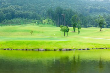 Göl manzarası ve yeşil çimenli golf sahası 