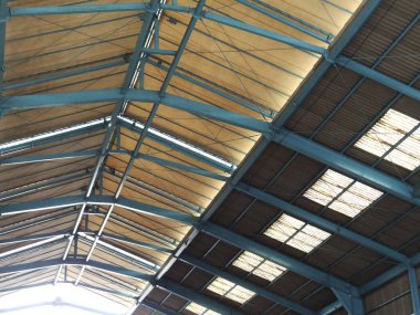 Mavi çelik kirişler tavan pencereleri ve ahşap paneller içeren sanayi deposu tavanı