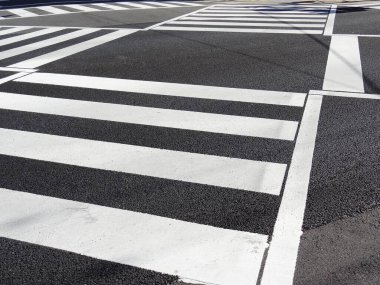 Asfalt yolda yaya geçidinde beyaz çizgiler.