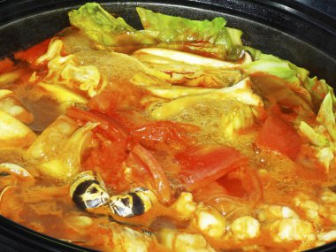 Sebzelerle kaynayan renkli deniz ürünleri güveci.