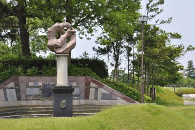 Halka açık bir parkta silindirik bir kaldırımda soyut taş heykel