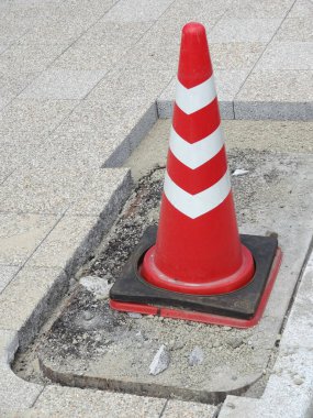 Parlak turuncu trafik konisi hasarlı kaldırım alanını gösteriyor