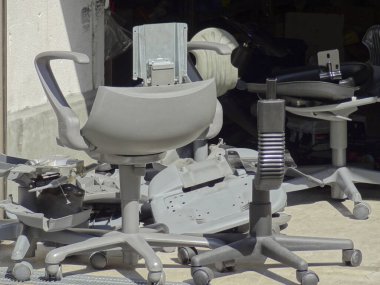 Bina duvarının yanında duran parçalanmış ofis sandalyeleri.