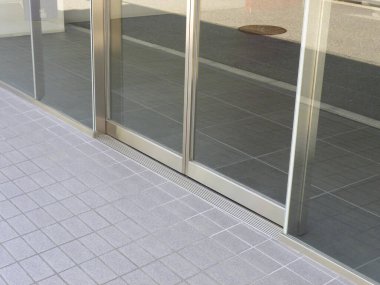 Cam kapıları yansıtan, kaldırıma serpiştirilmiş bir toplantı.