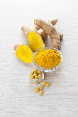 Beyaz arkaplanda zerdeçal kökü ve tozu var.