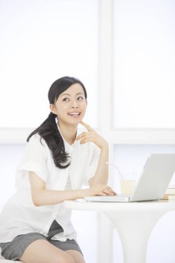 İç mekanda dizüstü bilgisayarla çalışan Asyalı güzel bir kadının portresi.