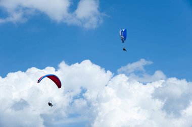 Mavi gökyüzünde uçan iki paraşütçü