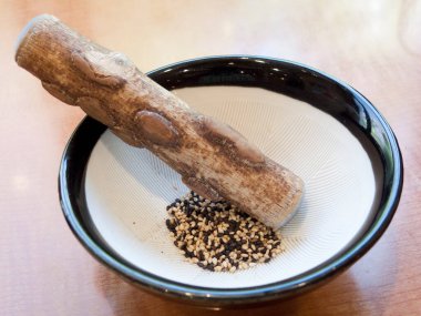 Ahşap tokmak kasede susam tohumu öğütüyor.