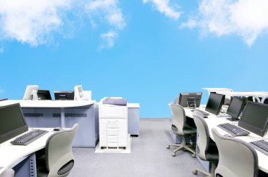 Mavi gökyüzüne karşı bilgisayarları ve masaları olan ofis 