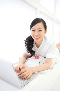 Bilgisayarda çalışan gülümseyen Asyalı kadın 