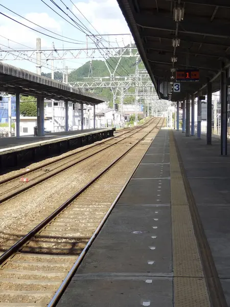 Uzak yeşil tepeye doğru uzanan boş tren istasyonu platformu