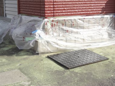 Dışarıdaki kırmızı binanın köşesindeki tuğlaları kaplayan plastik kaplama.