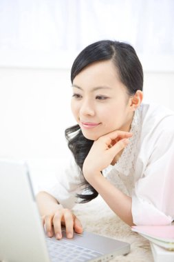 Göz kamaştırıcı bir Japon kadının portresi. Parlak beyaz bir odada dizüstü bilgisayarla çalışıyor..