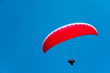 Mavi gökyüzünde uçan kırmızı paraglider