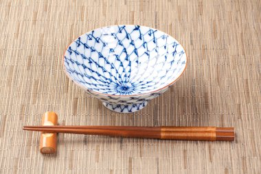 Bambu hasırının üzerinde seramik kase ve çubuklar