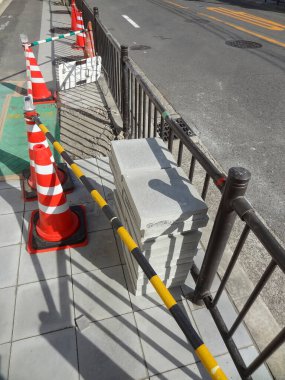 Trafik konilerinin yanındaki metal çitlerin yanına beton bloklar yığılmış.