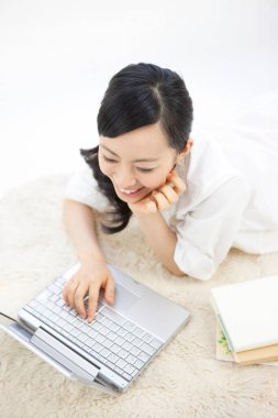 Göz kamaştırıcı bir Japon kadının portresi. Parlak beyaz bir odada dizüstü bilgisayarla çalışıyor..