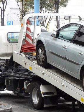 Gümüşten bir araba gündüz vakti çekiciye yükleniyor.