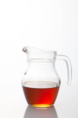 Beyaz arka planda şeffaf cam sürahide çay.