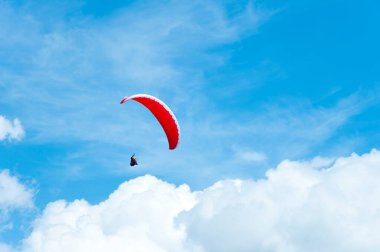 Mavi gökyüzünde uçan kırmızı paraglider