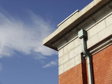 Kırmızı tuğla bina köşesi mavi gökyüzü arkaplanıyla buluşuyor