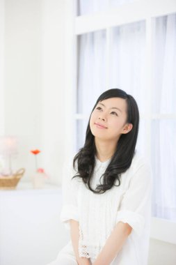 Zarif Japon kadın zarif bir şekilde minimalist beyaz bir odada poz veriyor..