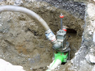 Endüstriyel su pompası dışarıda çamurlu kazı alanında çalışıyor.