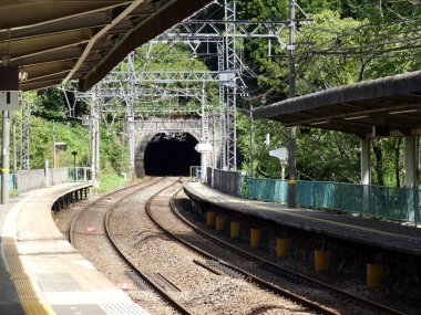 Somut sütunlar rayları destekliyor, hareketli şehir içindeki demiryolu koridorunu görsel olarak tanımlıyor.