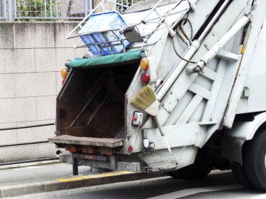 Şehir sokağının yakınındaki çöp kamyonunun arka görüntüsü.