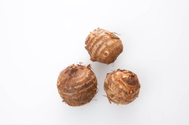 Beyaz arkaplanda dinlenen üç çiğ taro kökü