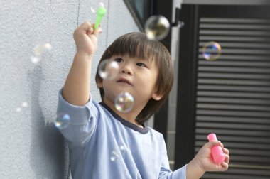 Şehir sokaklarında sabun köpükleri olan küçük bir çocuk. 