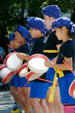 Asyalı çocuklar okul geçidinde davullarla gösteri yapıyorlar. 
